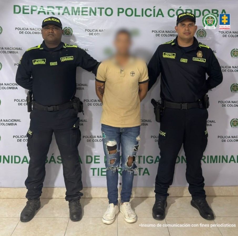 En la imagen aparece un hombre de jean y camiseta amarilla, entre dos uniformados de la Policía. 