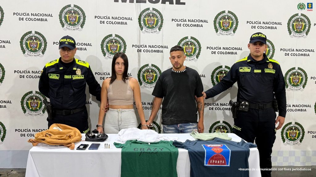 En la fotografían a parecen de pie, en hilera y esposados entre sí John Wilson Zuluaga Ruíz, Nathali Ruíz Rivas. La mujer viste con blusa tipo ombliguera, de olor piel y jean azul claro, usa cabello largo hasta los hombros y se peina por la mitad. El hombre usa camiseta de color negro con letras blancas en el cuello; jean azul desgastado y usa barba tipo candado. Delante de ellos hay una superficie blanca y sobre ella hay celulares, prendas de vestir, un morral, munición. En los extremos hay uniformados de la Policía Nacional. Detrás de ellos hay un pendón institucional de la Policía.