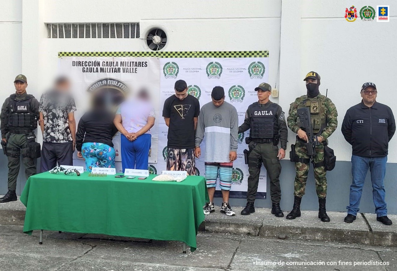 En la foto aparece de pie y con la cabeza agachada, José Ramiro Giraldo Silva, alias ‘Ramiro’; y Harrison David Montes Córdoba. Uno de ellos viste camiseta de manga corta color negra y pantalón estampado. La otra persona viste buzo de manga larga gris con granja blanca horizontal y pantaloneta estampada. Al lado derecho de ellos hay un uniformado del Gaula Policía y a su izquierda hay otro uniformado del Gaula Policía, uno del Ejército y un servidor del CTI de la Fiscalía. Delante de ellos hay una mesa con mantel verde y sobre ella hay dos armas de fuego, munición, tres teléfonos celulares y una bolsa plástica. También hay letreros que dicen ‘munición, celulares, y base de coca’. Detrás de ellos hay un pendón institucional de la Policía.