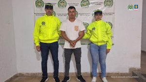 en la imagen se ve una persona detenida bajo custodia de dos uniformados de la Policía Nacional. 
