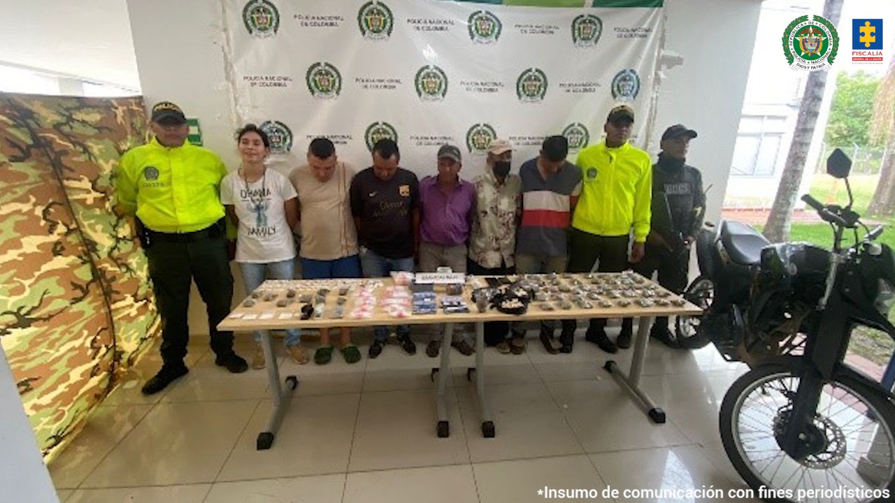 En la foto aparecen los seis presuntos integrantes de ‘Los Fantásticos’. A lado y lado de ellos hay tres uniformados de la Policía Nacional. Delante de ellos, sobre una mesa hay diversos elementos como estupefacientes y dinero. Al lado de la mesa hay una motocicleta. Detrás de ellos hay un pendón institucional de la Policía.