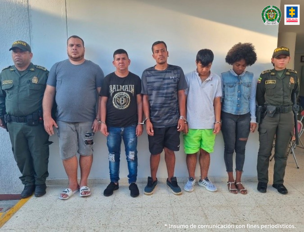 En la foto aparecen, de pie, los cinco presuntos responsables de falsificar documentos de identidad.  A lado y lado de ellos hay dos uniformados de la Policía Nacional. 