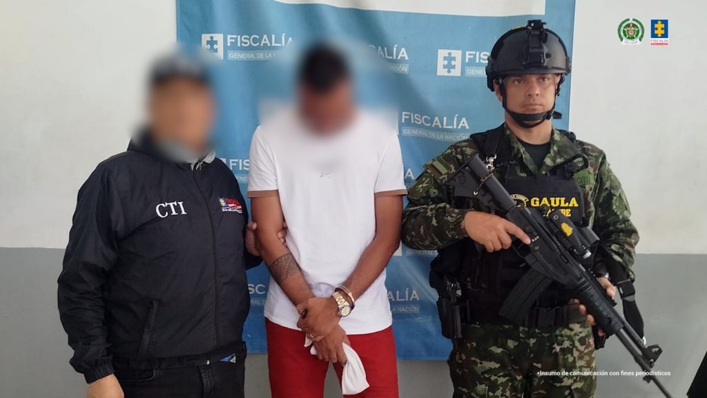 Funcionarios del CTI Atlántico y de la Ejército Nacional, custodian al procesado de camisa blanca y cabeza gacha. 