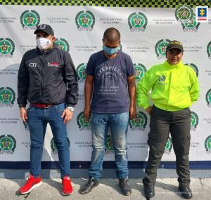 En la foto aparece de pie Wilder Alexis Sinisterra Rivas, alias ‘Makuto’. Viste camiseta de manga corta azul con estampado circular blanco a la altura del pecho; jean azul y zapatos oscuros. Al lado derecho de él hay un servidor del CTI de la Fiscalía y a su izquierda un uniformado de la Policía Nacional.