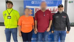 En la imagen se aprecia a los capturados con el rostro difuminado junto a investigador del CTI y uno de la Sijin. En la parte posterior se observa el banner que identifica a la Fiscalía General de la Nación