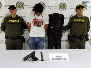 En la fotografía aparecen los dos capturados junto a dos agentes de la Policía Nacional. En la parte posterior aparece una mesa con una pistola traumática y munición 