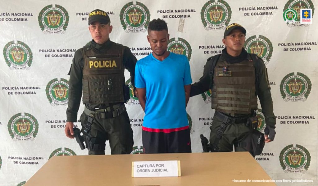 En la fotografía aparece el capturado junto a dos agentes de la Policía Nacional. En la parte superior está un banner de la Policía Nacional 