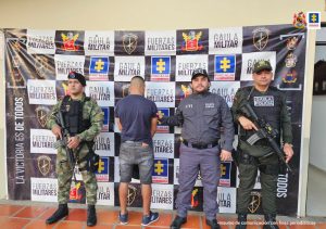 En la imagen se ve una persona detenida bajo custodia de integrantes del CTI, Policía y Ejército, componente Gaula. Detrás suyo backings institucionales.