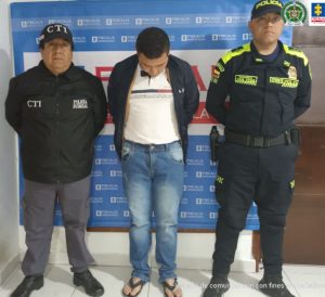 En la fotografía aparece el capturado junto a un servidor del CTI y un agente de la Policía Nacional. En la parte superior está un banner de la Fiscalía General de la Nación