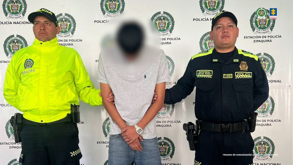 En la imagen aparece el judicializado de frente y en medio de dos integrantes de la Policía Nacional. El procesado tiene el rostro con efecto BLUR. 