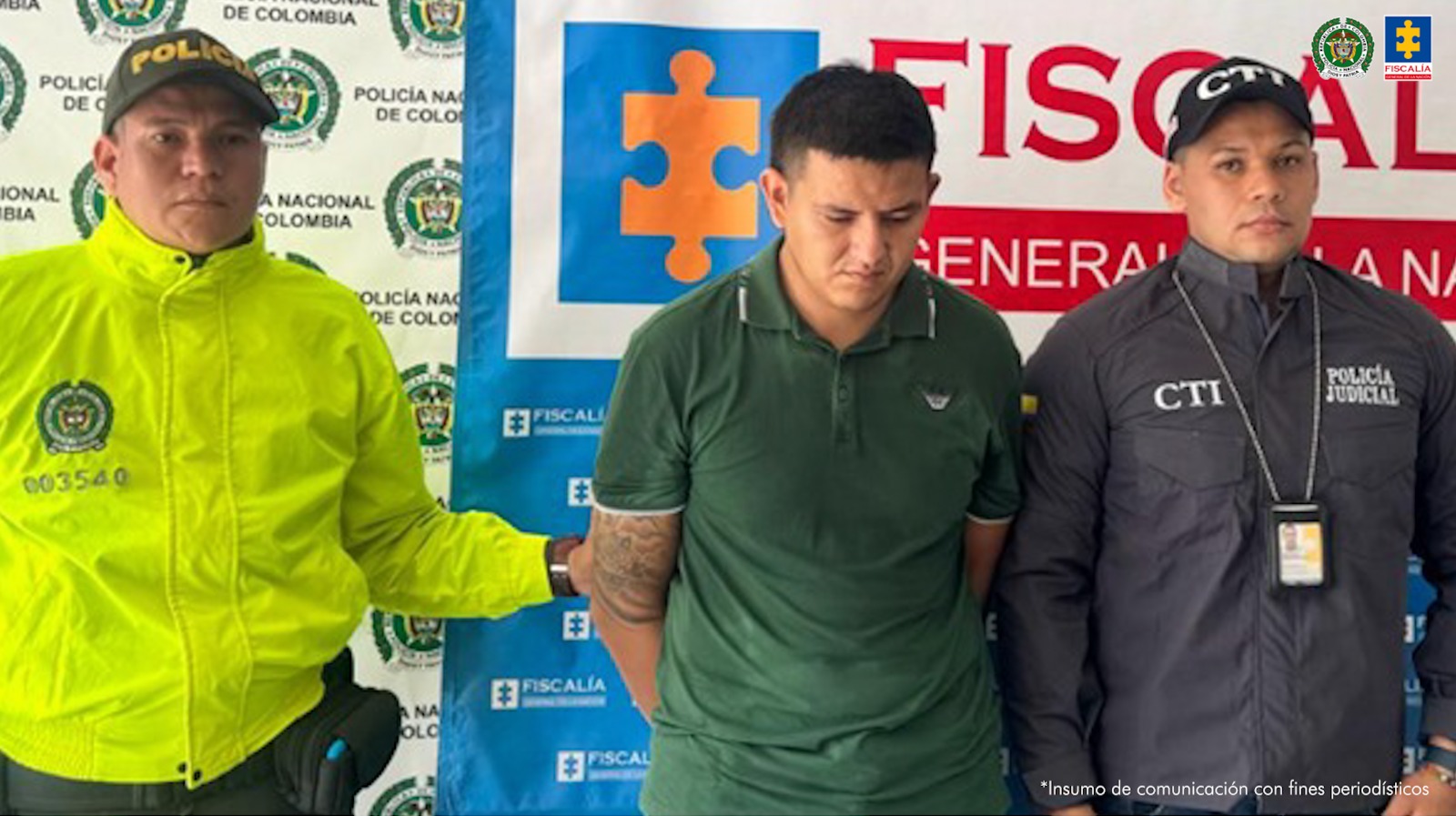 En la imagen se ve una persona detenida bajo custodia de dos uniformados de la Policía Nacional. Detrás suyo un backing institucional.