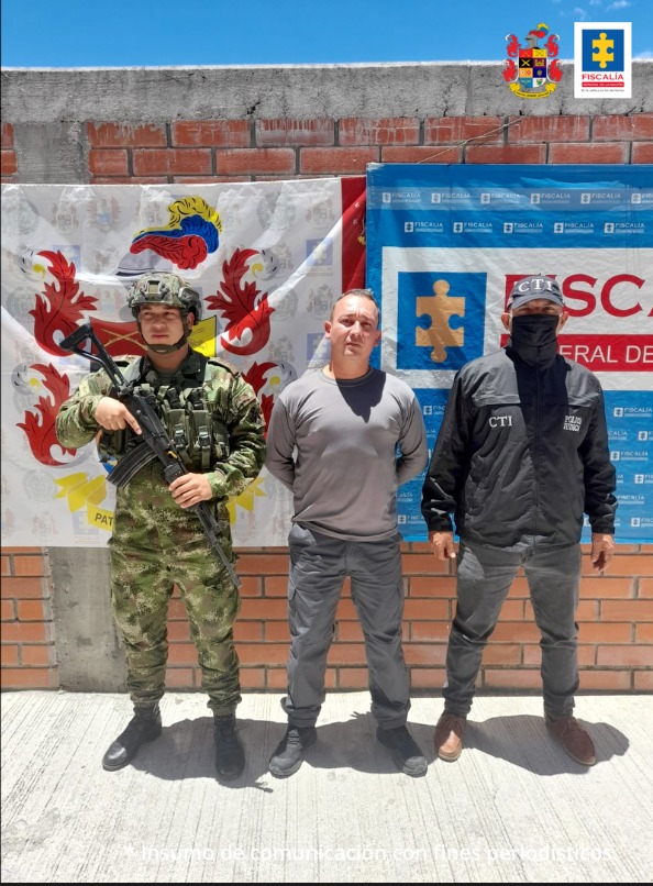 En la imagen se ve una persona detenida bajo custodia de servidores del CTI y del Ejército. Detrás suyo, backings institucionales.