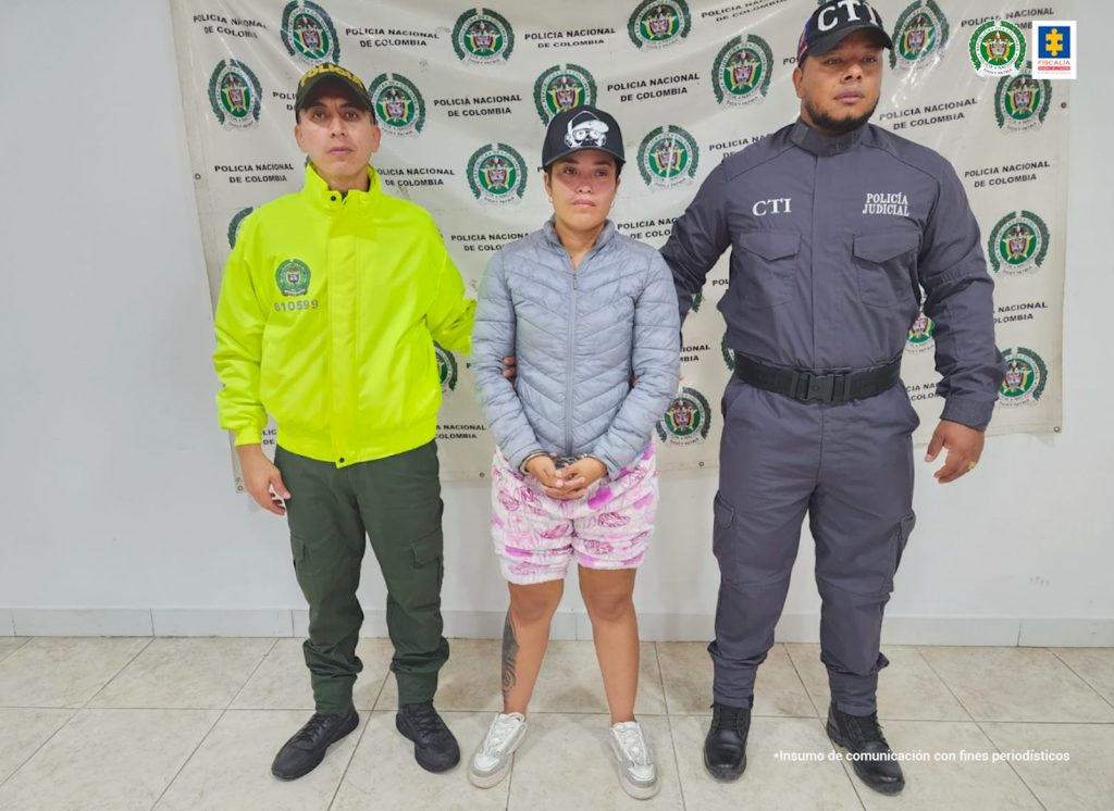 en la imagen se ve una mujer detenida bajo custodia del CTI y la Policía. Detrás suyo un backing institucional. 