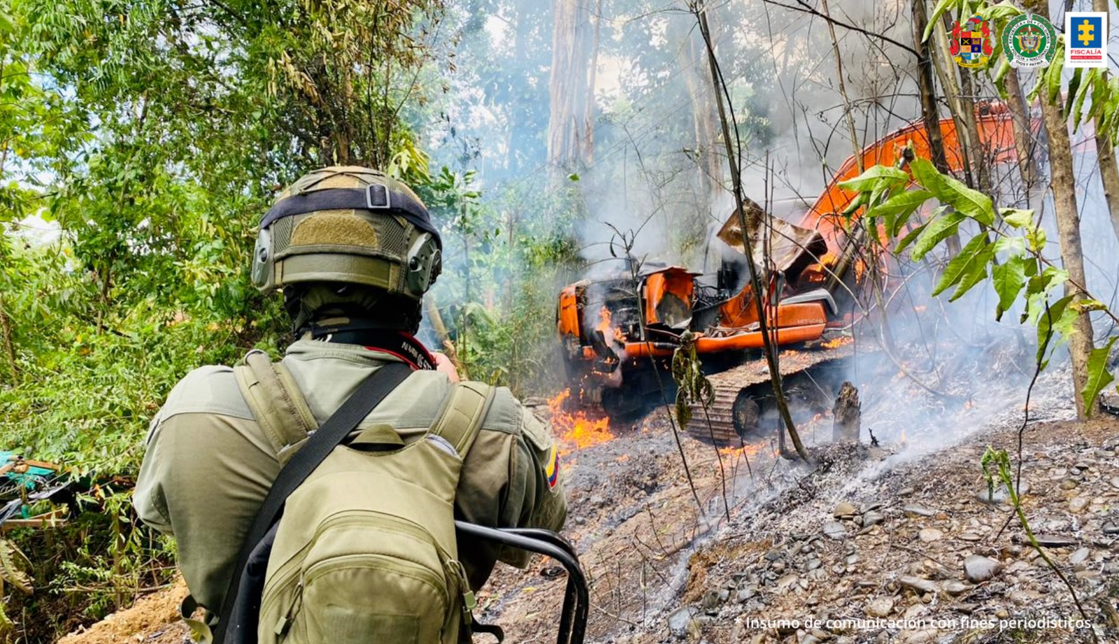 Policía realiza procedimineto de destrucción de una retroexcavadora, se ve al uniformado fotografiando a la máquina en llamas, producto de la explosión.