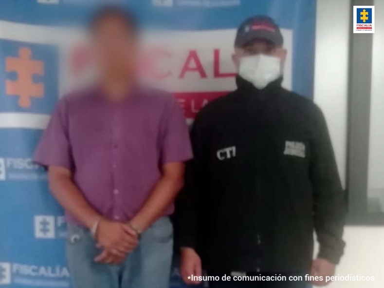 En la fotografía aparece el capturado con el rostro difuminado junto a un investigador del CTI. En la parte posterior se observa el banner de la Fiscalía General de la Nación.